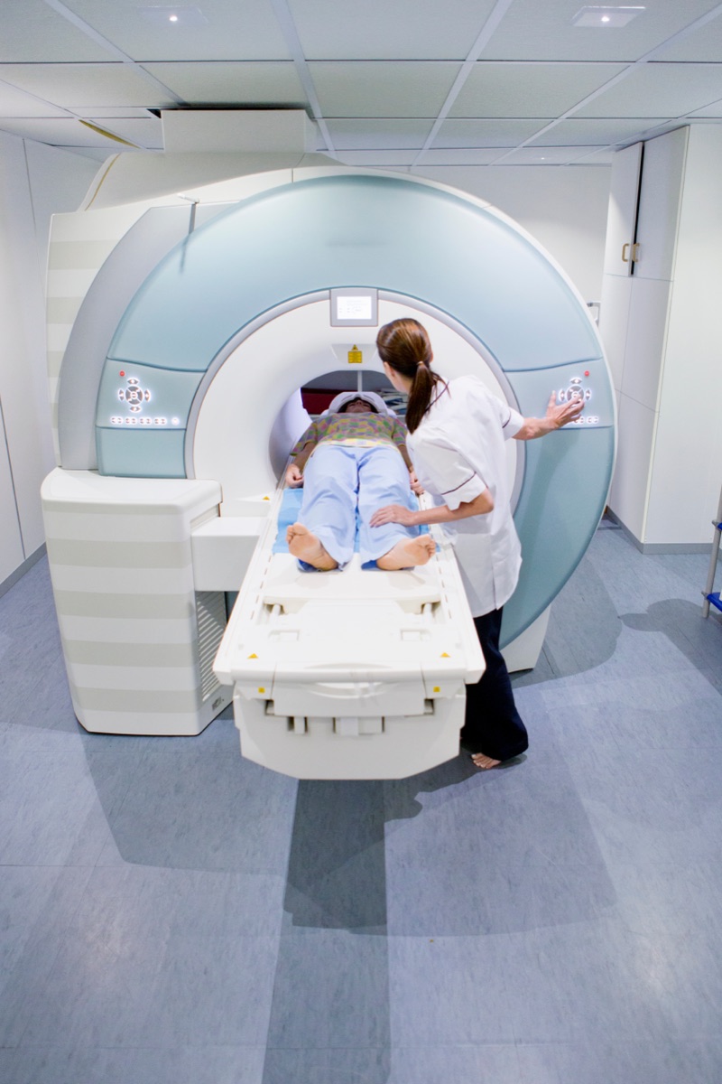 A radiographer guides a patient onto the bed of an advanced 3 Tesla MRI scanner in a London imaging suite